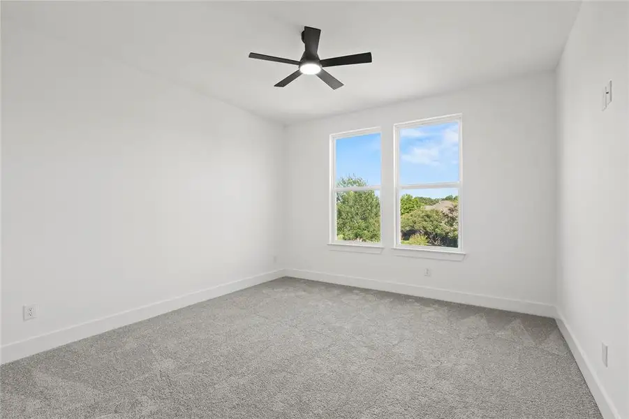 Carpeted empty room with baseboards and a ceiling fan