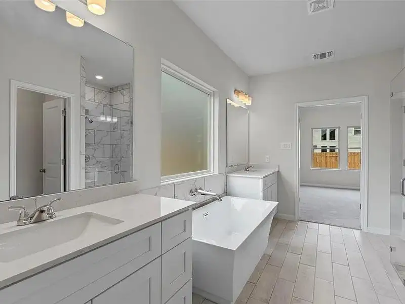 Indulge in a primary bathroom featuring dual vanities and a serene soaking tub, creating a spa-like retreat.