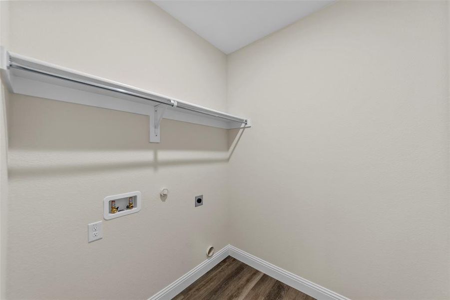 Dedicated utility space featuring a built-in shelving unit with hanging rod, wood-finish flooring, and white baseboards