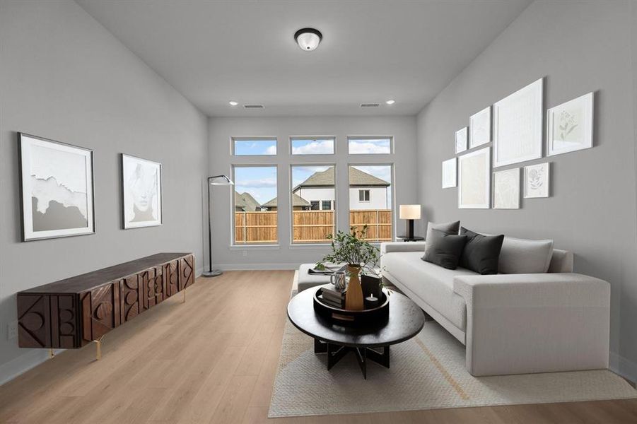 Spacious room featuring light wood-finish flooring, a series of large windows, and neutral gray walls Spacious room featuring light wood-finish flooring, a series of large windows, and neutral gray walls