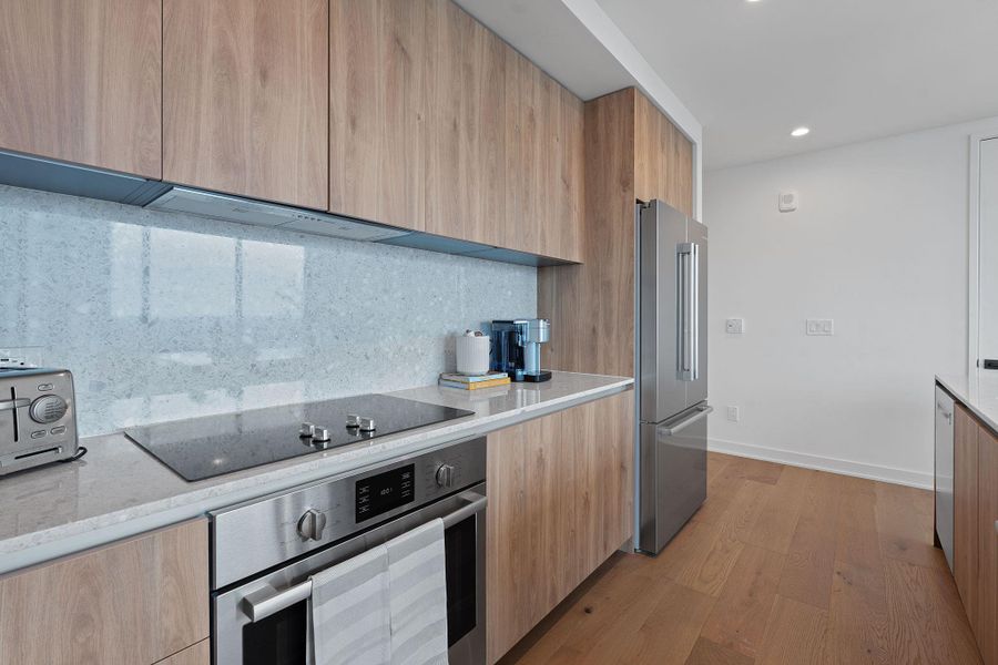Representative Photo. Kitchen featuring custom Italkraft cabninetry, terrazzo backsplash, waterfall-edge terrazzo countertops, stainless steel Bosch appliances, and pendant lighting above kitchen island