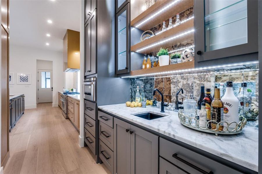 Bar with light wood-style flooring, recessed lighting, a sink, wet bar, and decorative backsplash Bar with light wood-style flooring, recessed lighting, a sink, wet bar, and decorative backsplash
