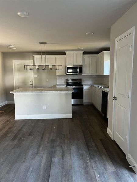 Kitchen with pendant lighting, white cabinets, range, dark hardwood / wood-style floors, and dishwashing machine