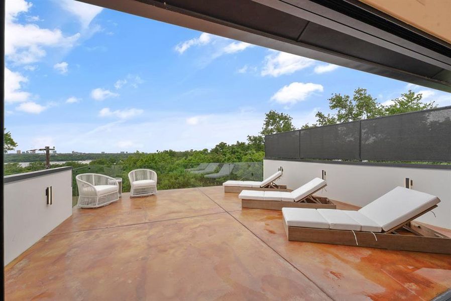 Expansive outdoor patio featuring stained concrete flooring and a partial glass railing