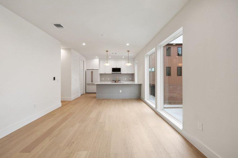 Kitchen featuring light countertops, white cabinets, open floor plan, decorative light fixtures, and light wood-type flooring