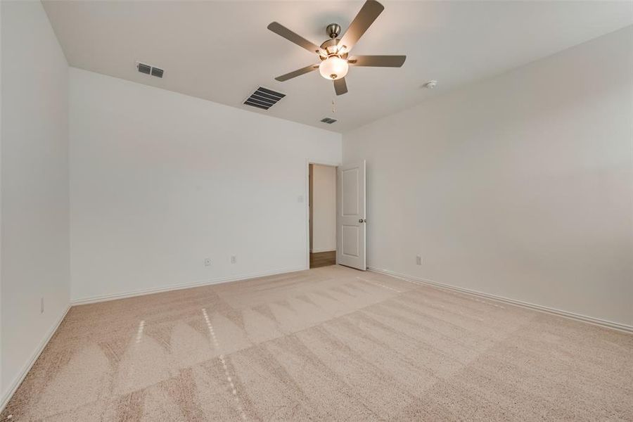 Empty room with ceiling fan and light carpet