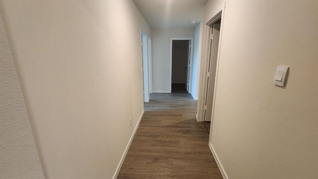 Hallway featuring wood-finish flooring, light neutral wall paint, and white trim molding