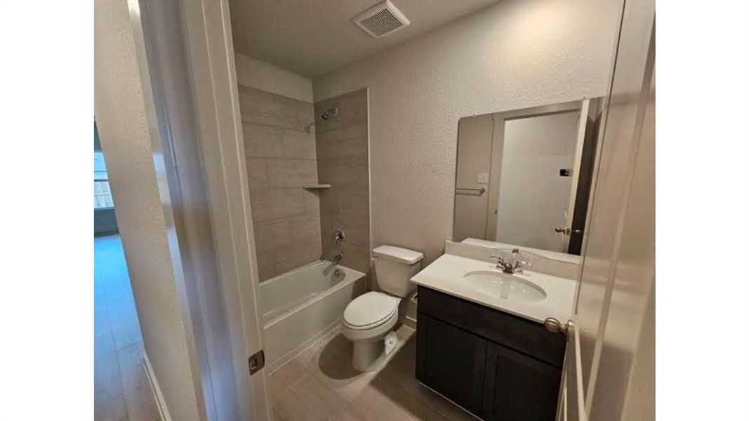 Full bathroom featuring a white tub, chrome fixtures, and light-toned tile surround with a built-in shelf Full bathroom featuring a white tub, chrome fixtures, and light-toned tile surround with a built-in shelf