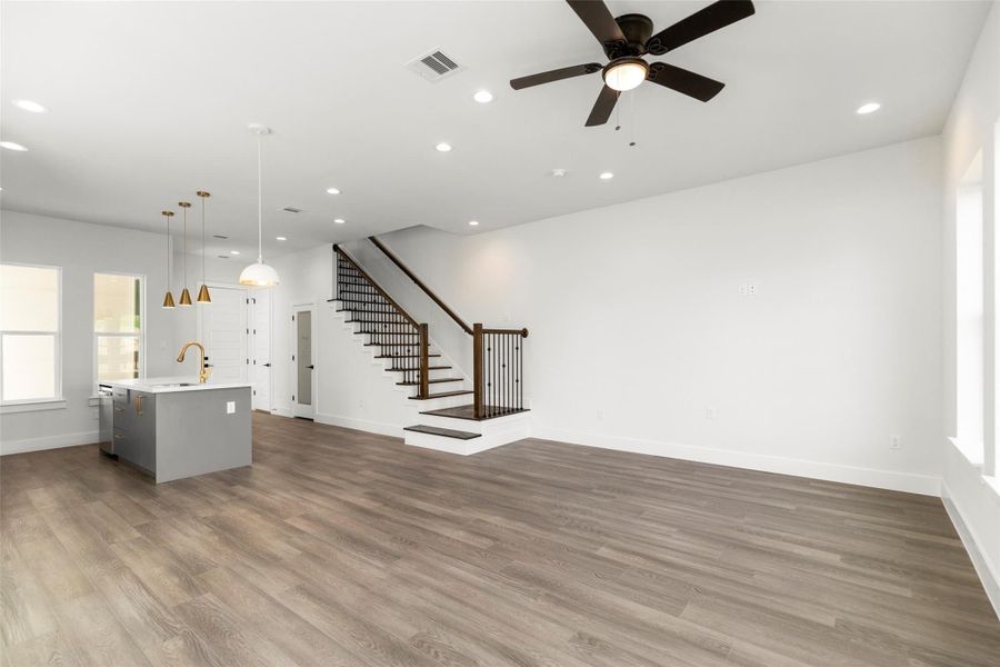 Open-concept living and dining area with stylish hardwood floors and a modern staircase. Open-concept living and dining area with stylish hardwood floors and a modern staircase.