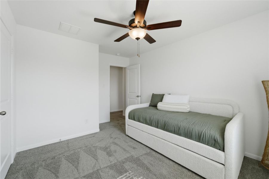 A comfortable bedroom with soft carpeting features a ceiling fan for climate control. A comfortable bedroom with soft carpeting features a ceiling fan for climate control.