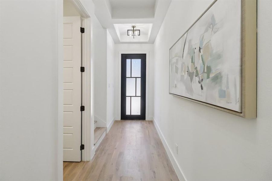 Doorway featuring light wood-type flooring and a tray ceiling