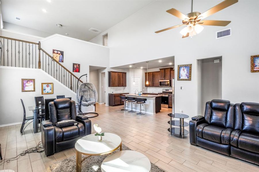 Living area featuring a high ceiling, wood finish floors, a ceiling fan, stairway, and recessed lighting Living area featuring a high ceiling, wood finish floors, a ceiling fan, stairway, and recessed lighting