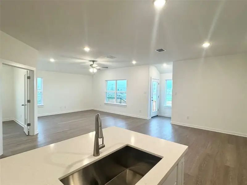 Kitchen with recessed lighting, open floor plan, dark wood finished floors, white cabinetry, and light stone countertops Kitchen with recessed lighting, open floor plan, dark wood finished floors, white cabinetry, and light stone countertops