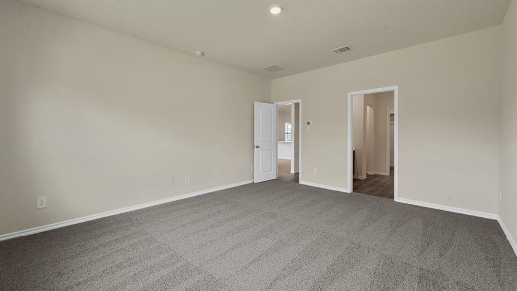 Spacious room featuring neutral wall tones and plush gray carpeting