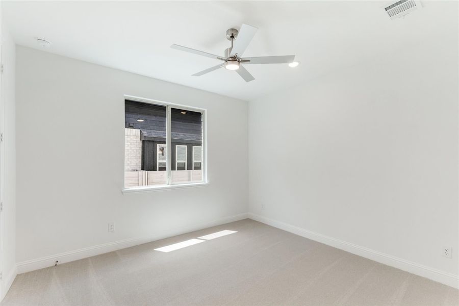 Empty bedroom with white walls, carpet flooring, ceiling fan, and single window