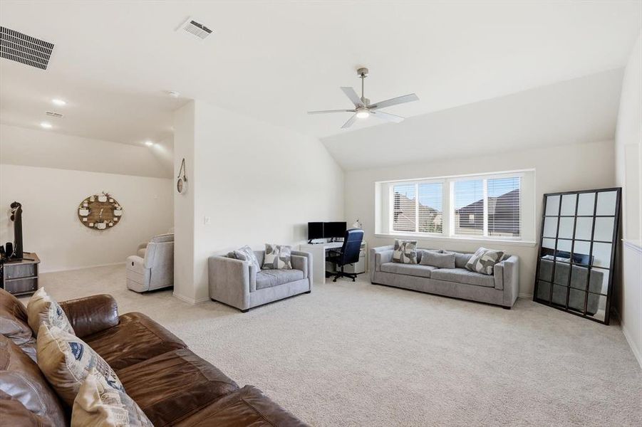 Spacious bonus room featuring vaulted ceilings, light-toned carpeting, a contemporary ceiling fan, recessed lighting, and multiple windows with horizontal blinds