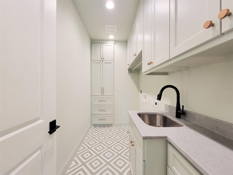 Spacious full-size laundry room featuring abundant storage cabinetry, a utility sink, and ample workspace for sorting, folding, and organization. Thoughtfully designed to combine functionality and convenience, this well-appointed space makes everyday household tasks effortless and efficient. Spacious full-size laundry room featuring abundant storage cabinetry, a utility sink, and ample workspace for sorting, folding, and organization. Thoughtfully designed to combine functionality and convenience, this well-appointed space makes everyday household tasks effortless and efficient.