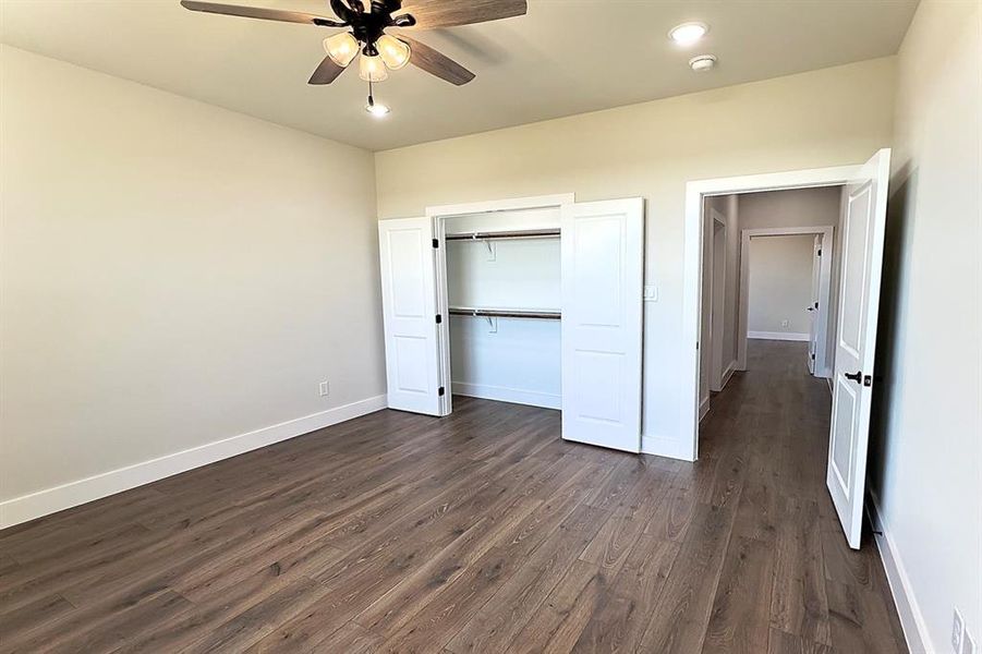 Unfurnished bedroom featuring dark finished floors, a ceiling fan, a closet, and recessed lighting