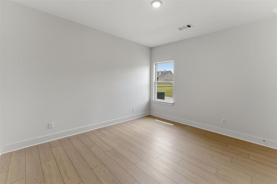 Bright interior space featuring light wood-finish flooring, crisp white walls, and a recessed ceiling light Bright interior space featuring light wood-finish flooring, crisp white walls, and a recessed ceiling light
