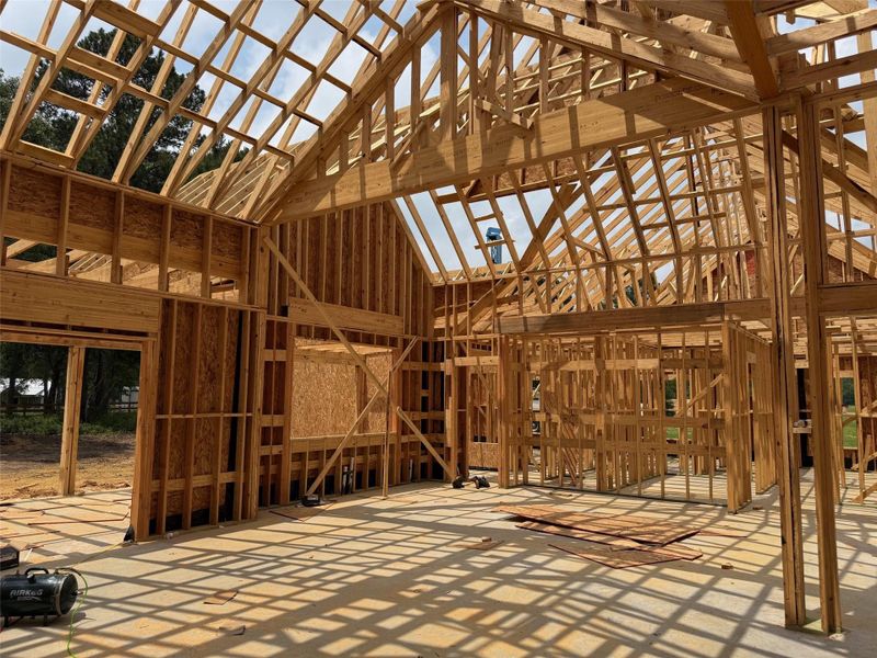 New construction framing featuring a high-pitch roofline, engineered wood trusses, and an open concept layout