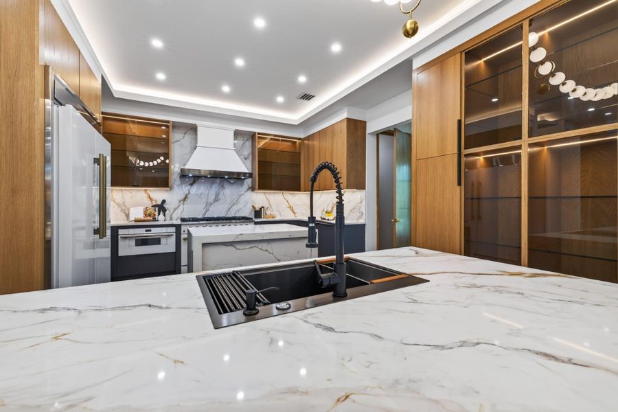 Statement kitchen featuring dramatic stone surfaces, custom cabinetry and an oversized island.