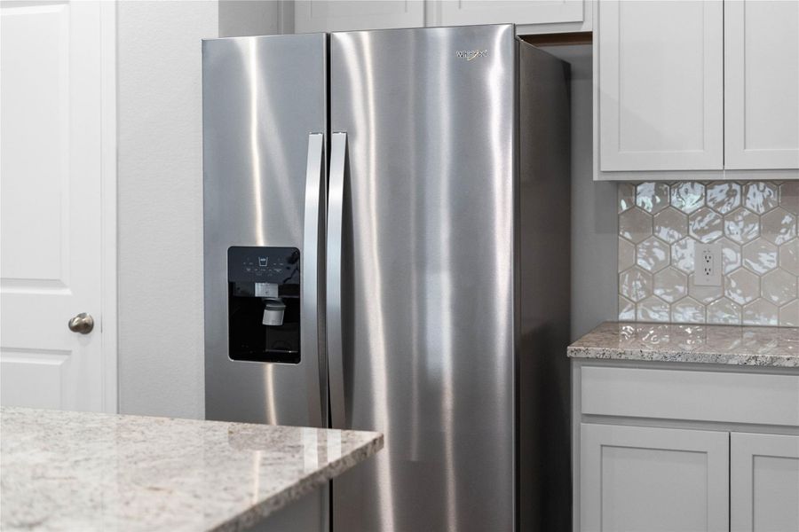 Kitchen comes equipped with a side-by-side Whirlpool refrigerator.