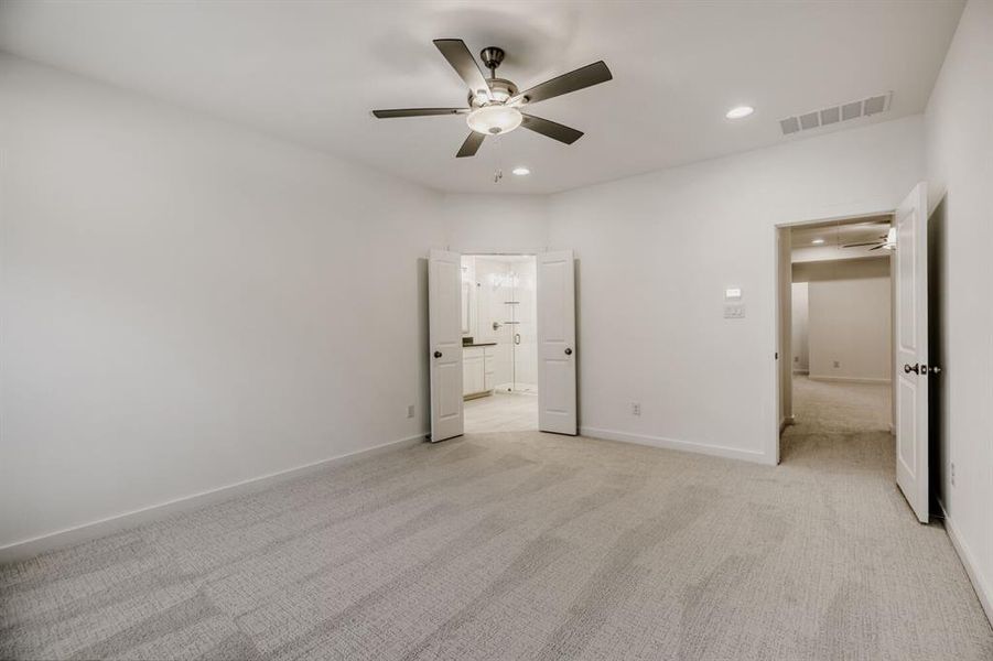 Spacious room featuring light-toned carpet flooring, a ceiling fan with integrated lighting, and recessed ceiling lights