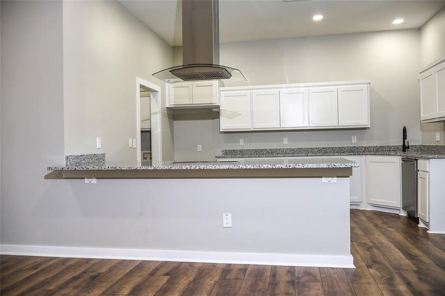 Kitchen featuring island exhaust hood, light stone counters, dark wood-style floors, white cabinets, and recessed lighting Kitchen featuring island exhaust hood, light stone counters, dark wood-style floors, white cabinets, and recessed lighting
