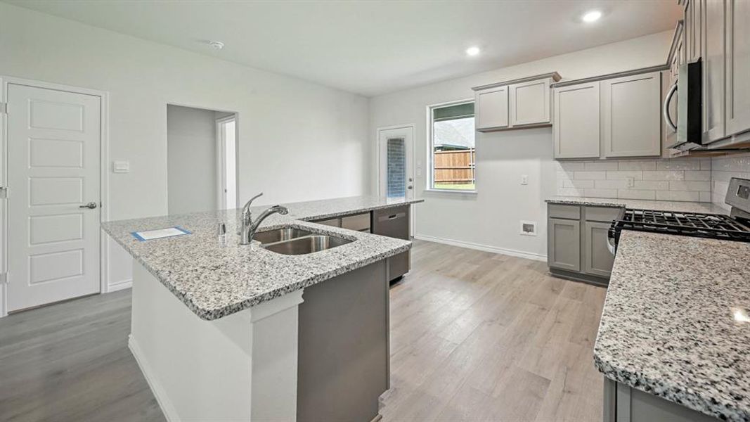 Kitchen featuring gray cabinetry, stainless steel appliances, light stone countertops, light wood finished floors, and recessed lighting Kitchen featuring gray cabinetry, stainless steel appliances, light stone countertops, light wood finished floors, and recessed lighting