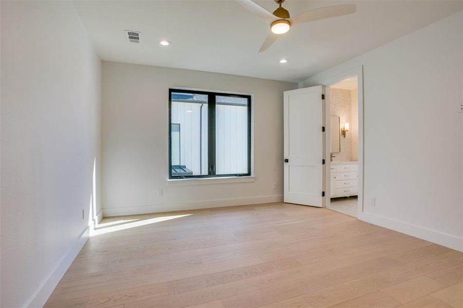 Secondary bedroom with ensuite bath, warm wood floors, and a comfortable, light-filled layout.
