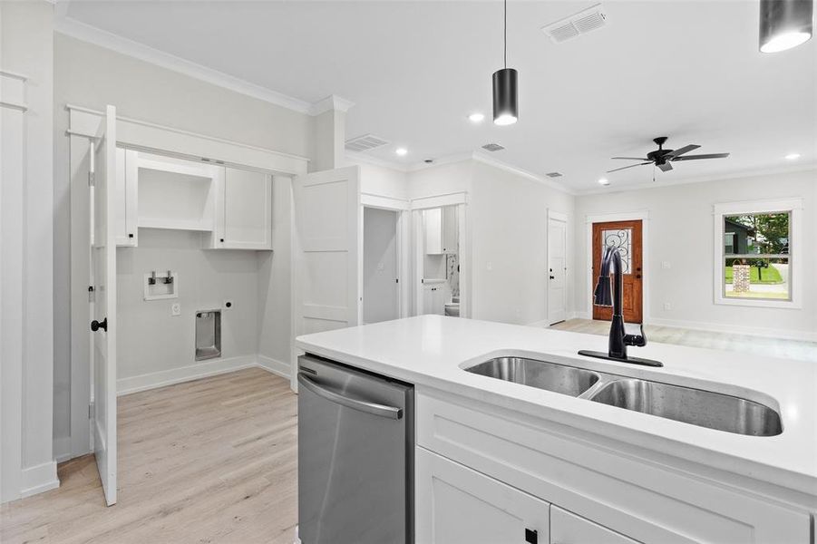 Kitchen with stainless steel dishwasher, ornamental molding, white cabinetry, light countertops, and recessed lighting