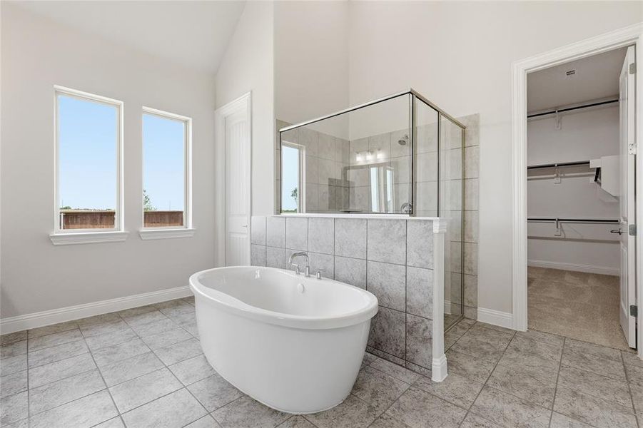 Bathroom with a stall shower, a walk in closet, a freestanding bath, tile walls, and light tile patterned floors Bathroom with a stall shower, a walk in closet, a freestanding bath, tile walls, and light tile patterned floors