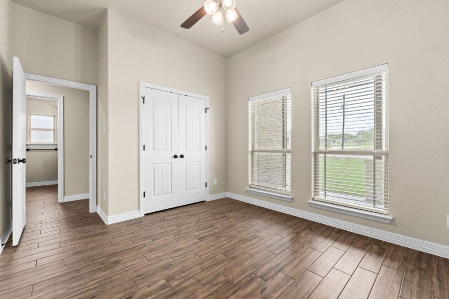 Spare room featuring dark wood like tile floors, lofted ceiling, and a ceiling fan, and a closet Spare room featuring dark wood like tile floors, lofted ceiling, and a ceiling fan, and a closet