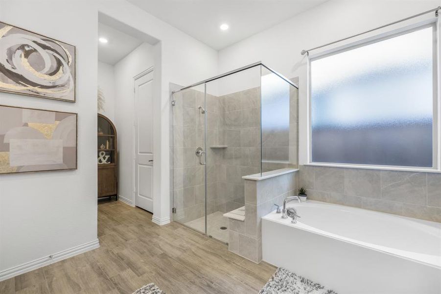 Full bath with a bath, light wood-type flooring, a stall shower, and recessed lighting Full bath with a bath, light wood-type flooring, a stall shower, and recessed lighting