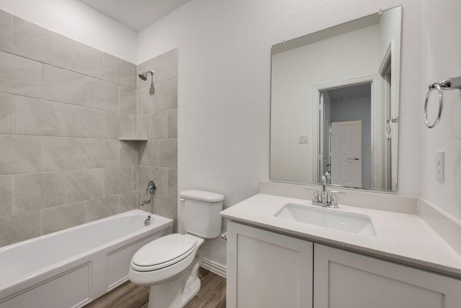 Full bathroom featuring oversized vanity, hardwood / wood-style flooring, toilet, and tiled shower / bath combo