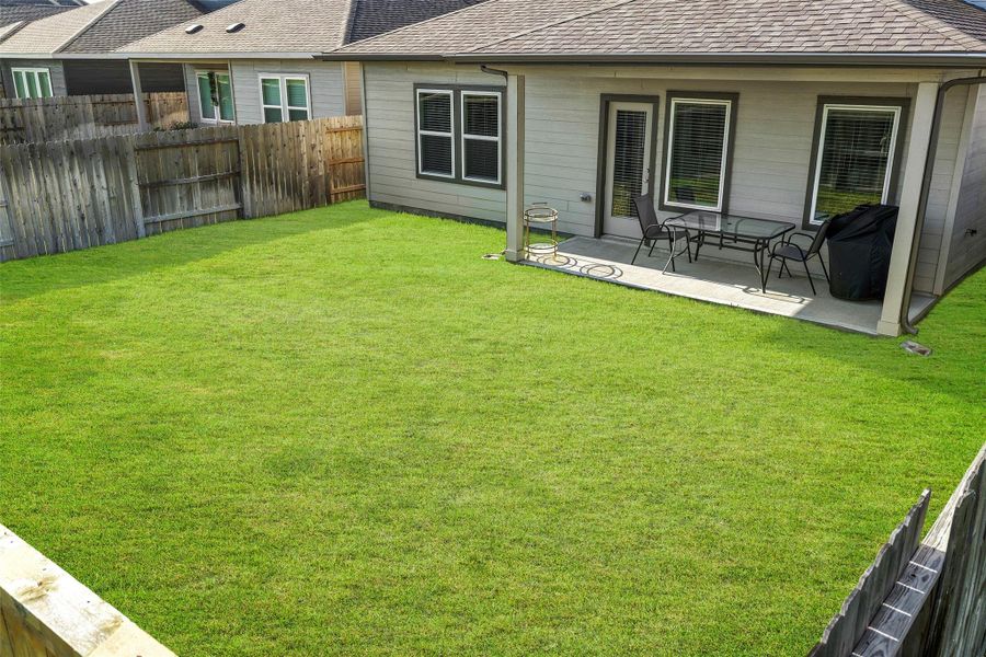 Spacious backyard with a cozy patio area, perfect for outdoor dining and relaxation.