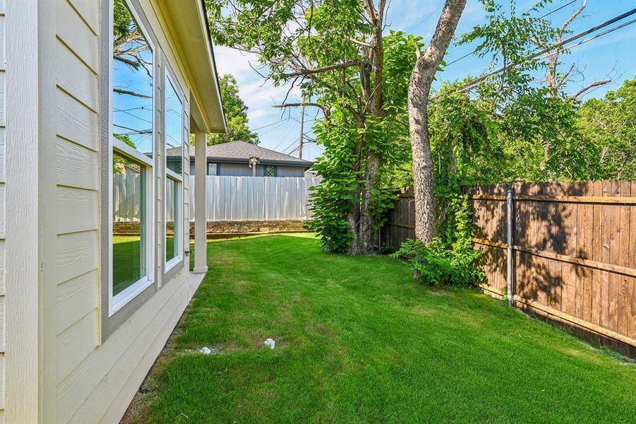 Expansive green lawn bordering the property, framed by a wood plank fence