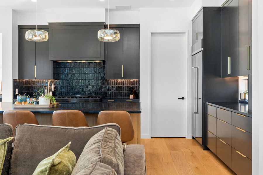 Kitchen featuring dark cabinetry, dark countertop, and a textured dark tile backsplash