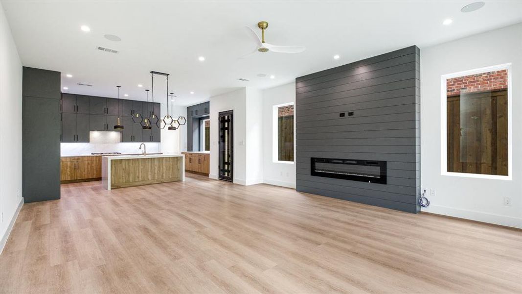 Unfurnished living room featuring ceiling fan, light hardwood / wood-style floors, sink, and a fireplace