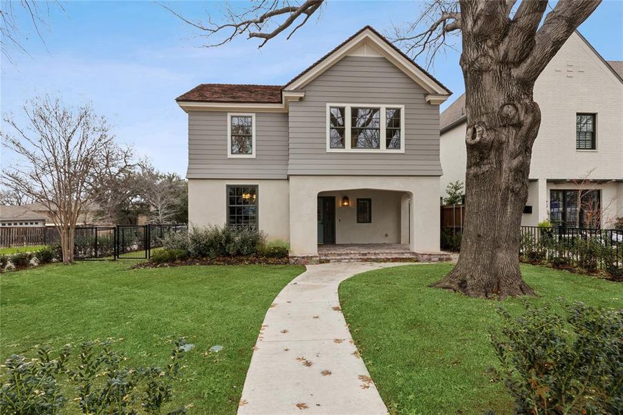 Traditional-style home with a front yard, fence, and stucco siding