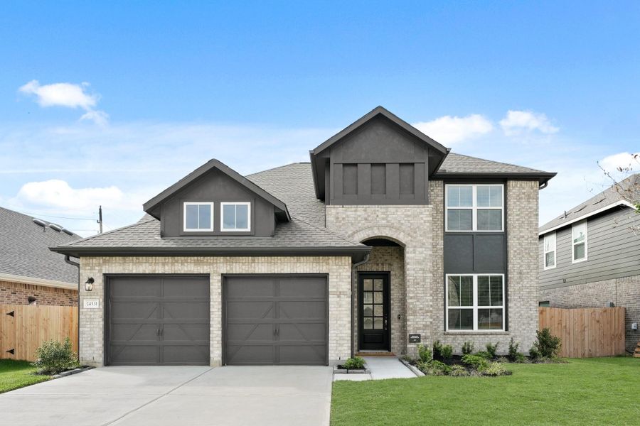 Timeless two-story elevation featuring a brick exterior, two car garage, and large windows for ample natural light.