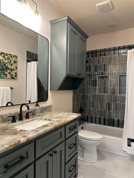 Modern bathroom featuring a rectangular undermount sink set in a patterned stone countertop, paired with a dark-finish faucet