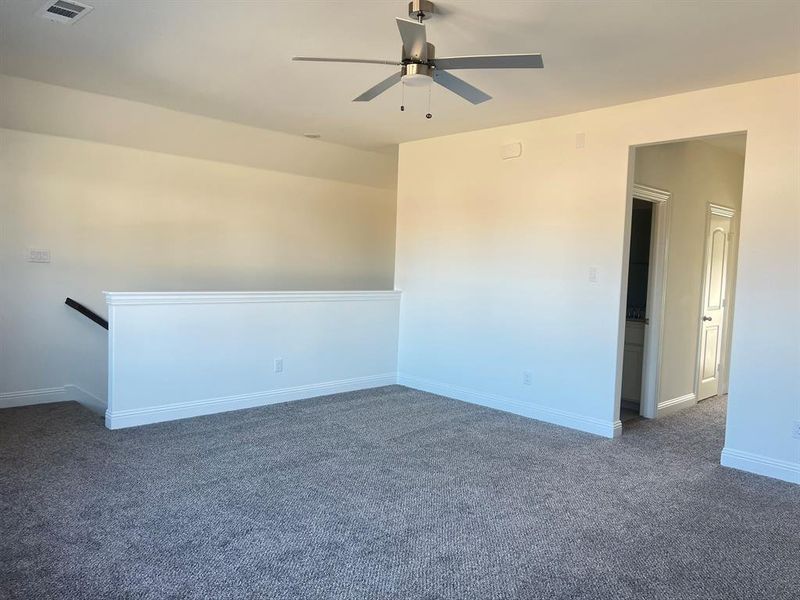 Upstairs loft with a bedroom and full bath, visible vents, baseboards, and a ceiling fan