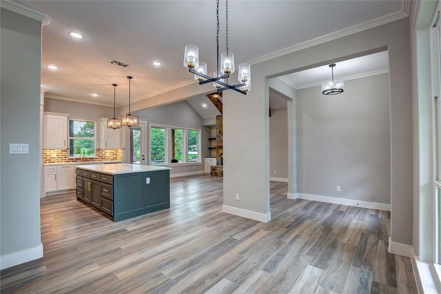 Kitchen featuring a kitchen island, white cabinetry, light hardwood / wood-style floors, and decorative light fixtures Kitchen featuring a kitchen island, white cabinetry, light hardwood / wood-style floors, and decorative light fixtures