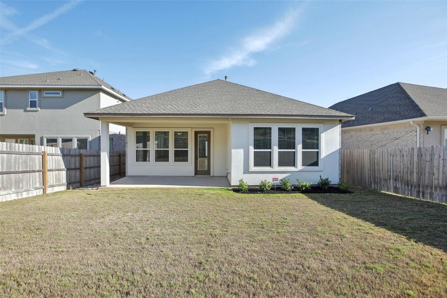 Rear view of property featuring stucco siding, a fenced backyard, a patio, and a yard