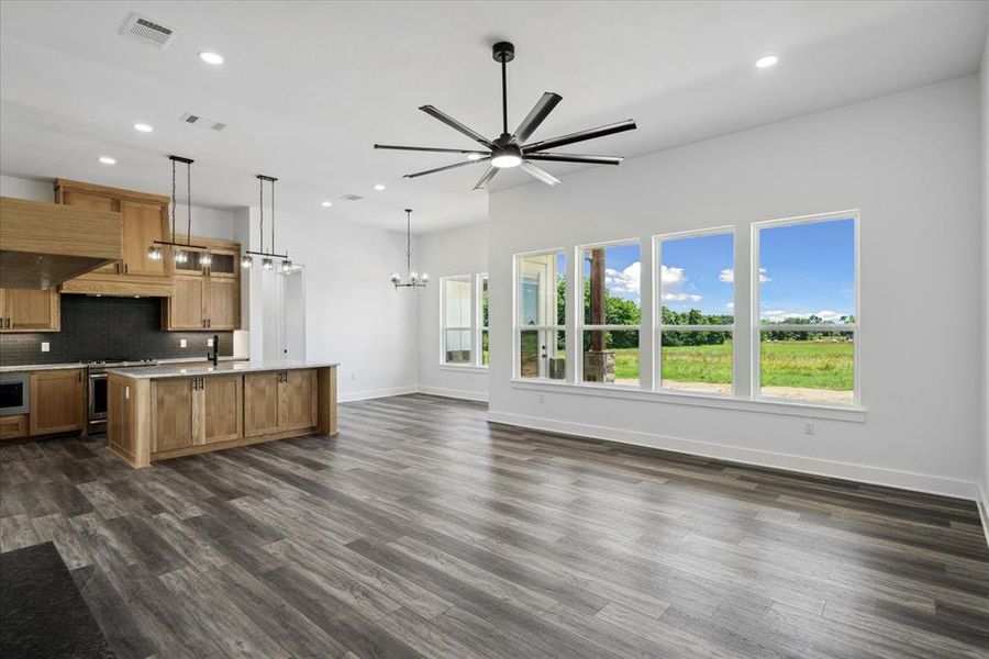 Kitchen with a chandelier, stainless steel gas stove, a kitchen island with sink, open floor plan, and decorative backsplash