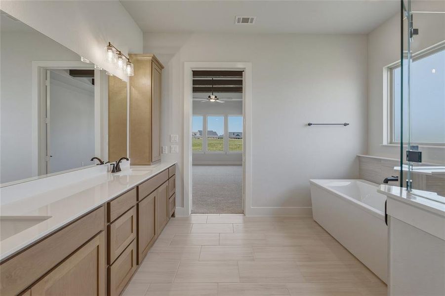 Bathroom featuring a dual vanity with light wood-finish cabinetry and white countertops Bathroom featuring a dual vanity with light wood-finish cabinetry and white countertops