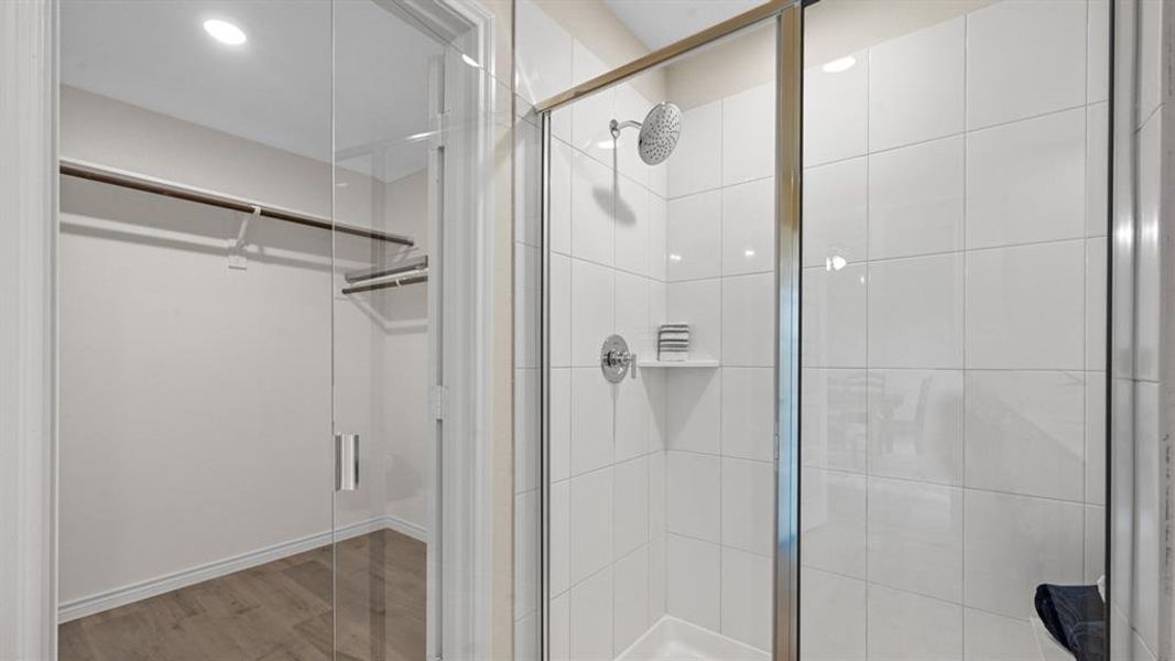 Full bathroom featuring a shower stall, light wood-type flooring, a walk in closet, and recessed lighting Full bathroom featuring a shower stall, light wood-type flooring, a walk in closet, and recessed lighting