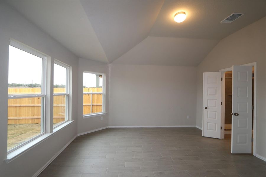 Empty room with vaulted ceiling and a wealth of natural light