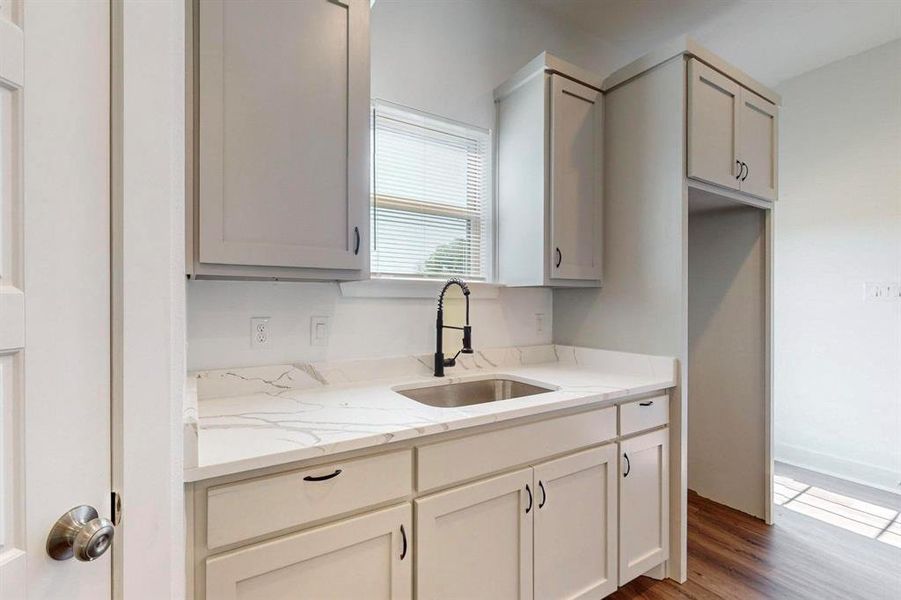 Kitchen with sink, dark hardwood / wood-style floors, and light stone counters